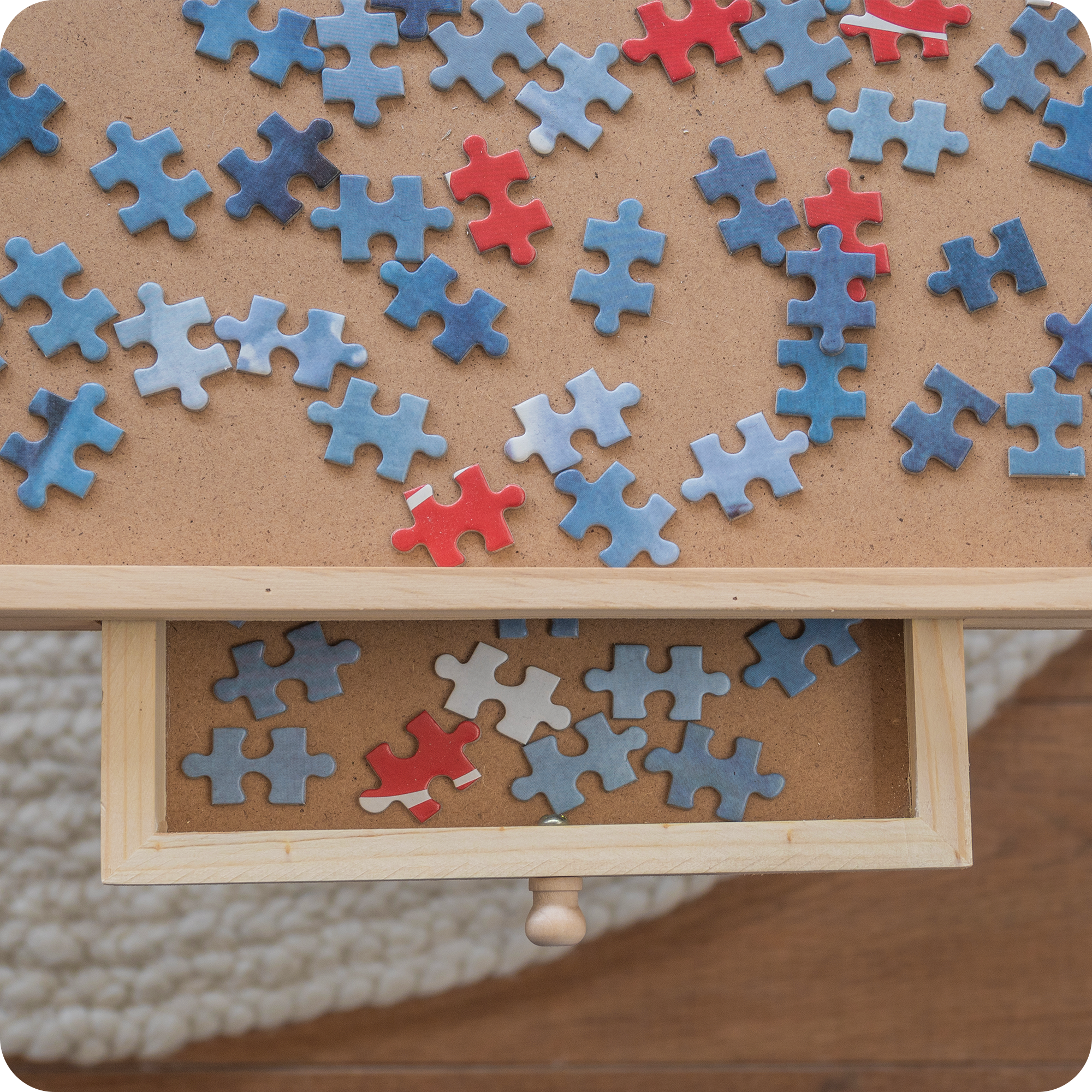 Gedetailleerd aanzicht van de puzzelplaat met puzzelstukjes erop. De lade is een beetje uitgeschoven waar ook puzzelstukjes in liggen.